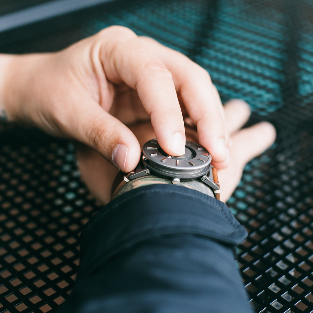 A person touching the raised markers of the Bradley Timepiece to tell time.