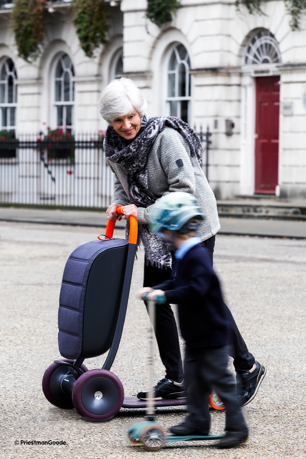 An older woman rides her Scooter for Life alongside her young grandson, who is riding a child’s scooter.