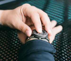 A person touching the raised markers of the Bradley Timepiece to tell time.